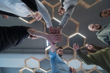 A group of young businessmen offer their hands together, symbolizing togetherness in the business...