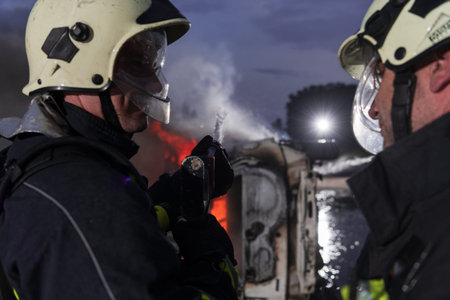 Firefighters using water fire extinguisher to fighting with the fire flame in car accident....