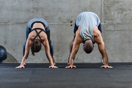 An attractive couple in the gym engaging in various stretching exercises together, showcasing their dedication to fitness, flexibility, and overall well-being. With synchronized movements, they demonstrate coordination, balance, and endurance while supporting and motivating each other on their fitness journeyの写真素材