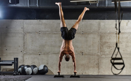 A muscular man in a handstand position, showcasing his exceptional balance and body control while...