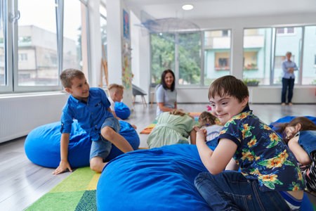 A happy female teacher sitting and playing hand games with a group of little schoolchildrenの写真素材
