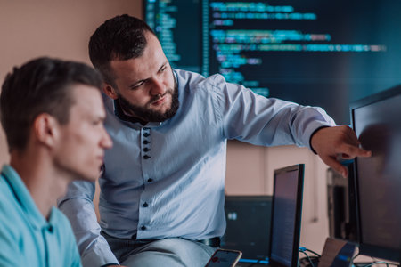 Programmers engrossed in deep collaboration, diligently working together to solve complex problems and develop innovative mobile applications with seamless functionality.の写真素材