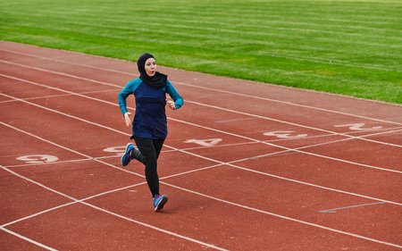 A muslim woman in a burqa sports muslim clothes running on a marathon course and preparing for upcoming competitionsの写真素材