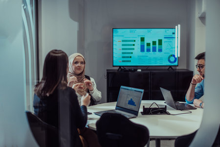 A group of young business entrepreneurs engages in a focused meeting, discussing various business strategies and collaboratively solving challenging problems, showcasing ambition, creativity, and teamwork in modern glass officeの写真素材
