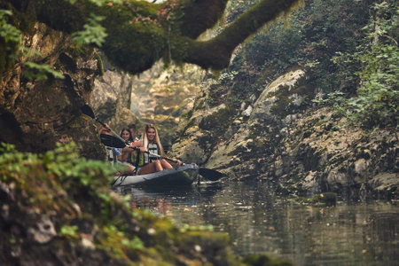 A group of friends enjoying having fun and kayaking while exploring the calm river, surrounding forest and large natural river canyonsの写真素材