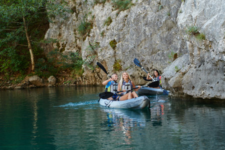 A group of friends enjoying having fun and kayaking while exploring the calm river, surrounding forest and large natural river canyonsの写真素材