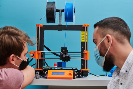 A group of colleagues collaborate in a lab while testing a 3D printer, demonstrating their commitment to technological advancement and scientific research.の写真素材