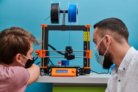A group of colleagues collaborate in a lab while testing a 3D printer, demonstrating their commitment to technological advancement and scientific research.の写真素材