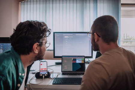 Programmers engrossed in deep collaboration, diligently working together to solve complex problems and develop innovative mobile applications with seamless functionality.の写真素材