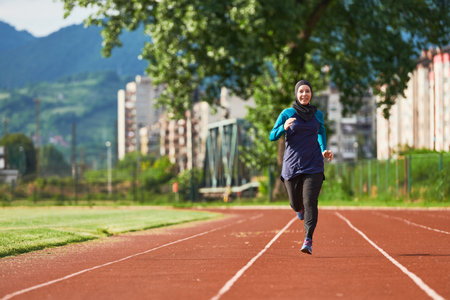 A muslim woman in a burqa sports muslim clothes running on a marathon course and preparing for upcoming competitionsの写真素材