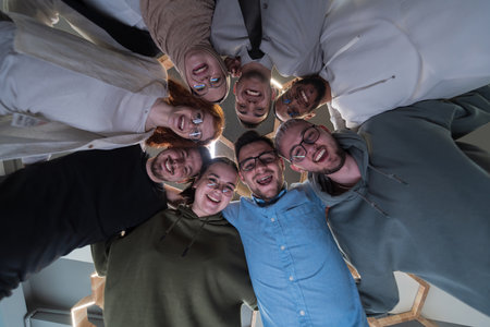 In a modern office, a group of young business professionals is captured in a warm and embracing hug, reflecting the spirit of unity, collaboration, and shared success in their dynamic workplace.の写真素材
