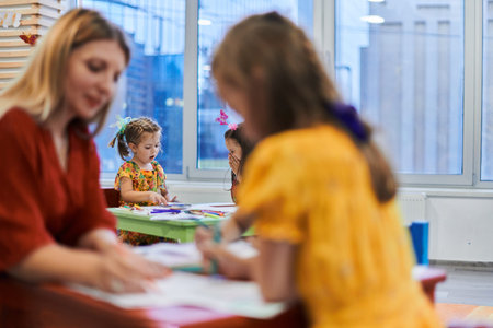 Creative kids during an art class in a daycare center or elementary school classroom drawing with...