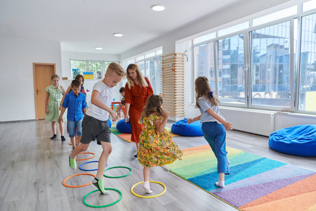 Small nursery school children with female teacher on floor indoors in classroom, doing exercise....