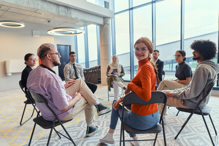 A diverse group of young business entrepreneurs gathered in a circle for a meeting, discussing...
