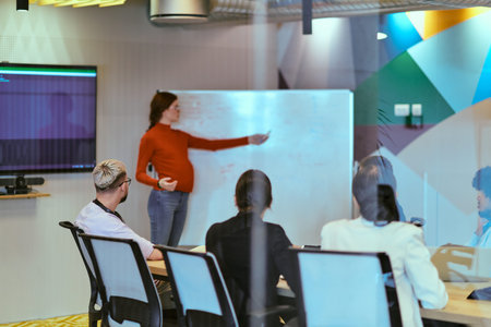 A pregnant business woman with orange hair confidently presents her business plan to colleagues in a...