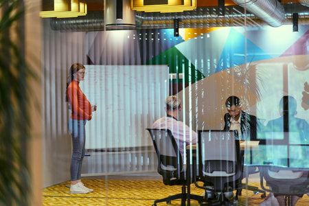 A pregnant business woman with orange hair confidently presents her business plan to colleagues in a modern glass office, embodying entrepreneurship and innovationの写真素材