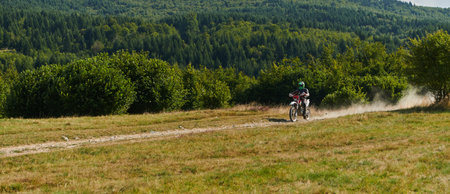 A professional motocross rider exhilaratingly riding a treacherous off-road forest trail on their motorcycle.の写真素材