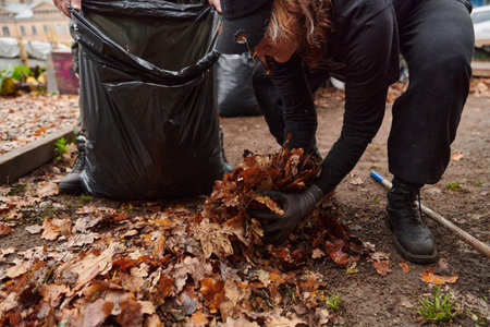 Father-daughter duo bonding in the garden as they work together to collect fallen leaves and fill up...