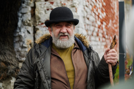An elderly man with a beard and a worn hat passionately imparts traditional values and cultural...