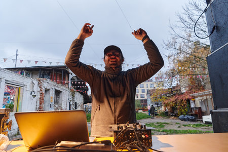 A young man is entertaining a group of friends in the backyard of his house, becoming their DJ and playing music in a casual outdoor gatheringの写真素材
