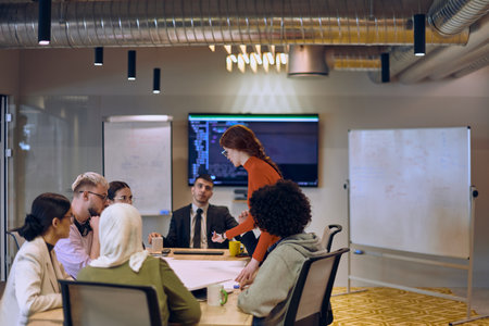 A diverse team of business experts in a modern glass office, attentively listening to a colleagues presentation, fostering collaboration and innovation.の写真素材