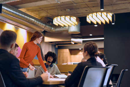A diverse team of business experts in a modern glass office, attentively listening to a colleagues...