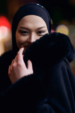 Muslim woman walking on an urban city street on a cold winter night wearing hijabの写真素材