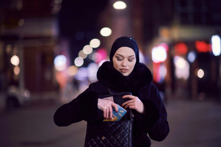 Muslim woman walking on an urban city street on a cold winter night wearing hijab