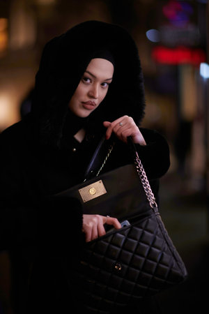 Muslim woman walking on an urban city street on a cold winter night wearing hijab