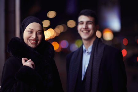 Happy multicultural business couple walking together outdoors in an urban city street at night near...