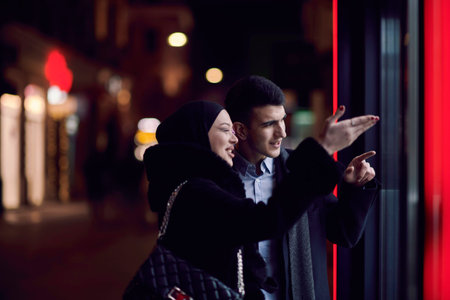 Happy multicultural business couple walking together outdoors in an urban city street at night near...