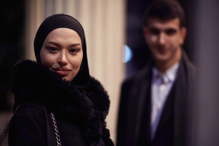 Happy multicultural business couple walking together outdoors in an urban city street at night near a jewelry shopping store window.の写真素材