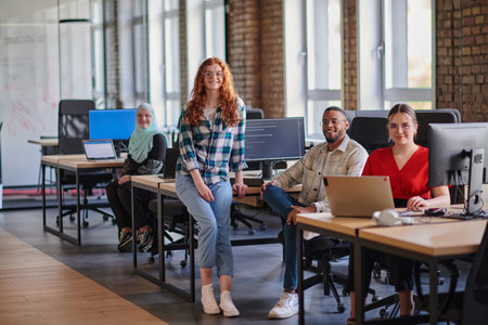 A diverse group of young business individuals congregates in a modern startup coworking center,...