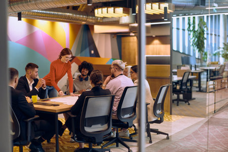 A diverse team of business experts in a modern glass office, attentively listening to a colleagues...