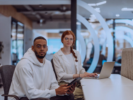 In a modern office setting, an African American businessman and his Muslim colleague, wearing a...