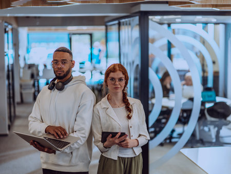 In a modern office African American young businessman and his businesswoman colleague, with her striking orange hair, engage in collaborative problem-solving sessionsの写真素材