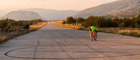 In the early morning light, the triathlete preparing for run by tying his shoes. With focused determination and unwavering dedication, he readies himself for the physical and mental challenge ahead, striving to push his limits and achieve his goals.の写真素材