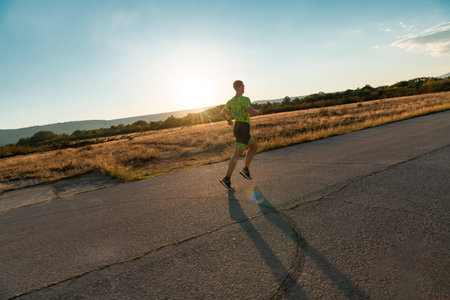 Triathlete in professional gear running early in the morning, preparing for a marathon, dedication...