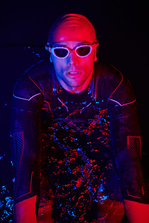 authentic triathlete swimmer having a break during hard training on night neon gel lightの写真素材