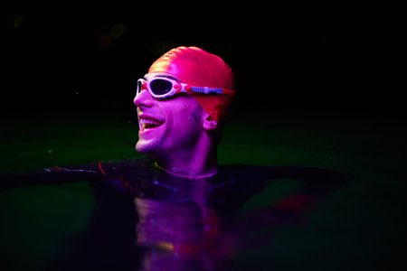 Authentic triathlete swimmer having a break during hard training on night neon gel lightの写真素材