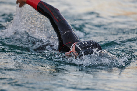 A professional triathlete trains with unwavering dedication for an upcoming competition at a lake, emanating a sense of athleticism and profound commitment to excellence.の写真素材