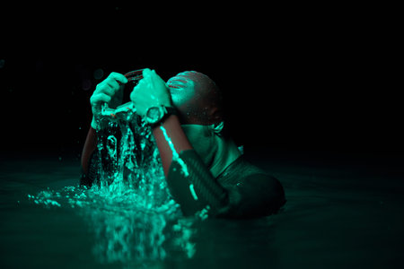 Authentic triathlete swimmer having a break during hard training on night neon gel light