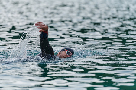 A professional triathlete trains with unwavering dedication for an upcoming competition at a lake, emanating a sense of athleticism and profound commitment to excellence.の写真素材