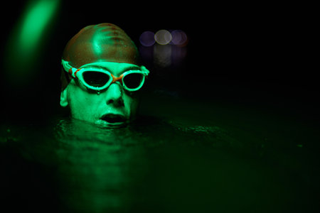 Authentic triathlete swimmer having a break during hard training on night neon gel lightの写真素材