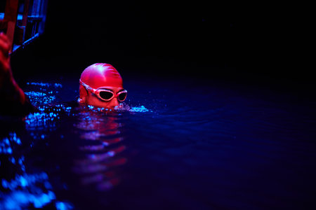 Authentic triathlete swimmer having a break during hard training on night neon gel lightの写真素材