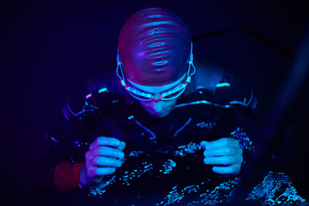 authentic triathlete swimmer having a break during hard training on night neon gel light