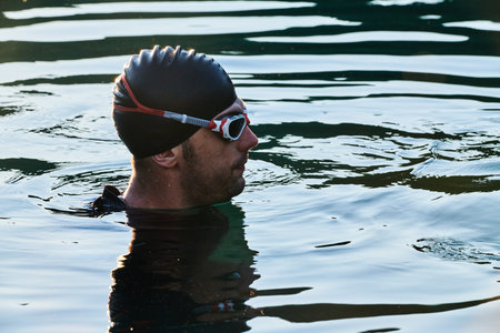A triathlete finds serene rejuvenation in a lake, basking in the tranquility of the water after an intense training sessionの写真素材