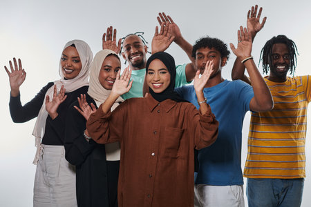 A jubilant and diverse group, including an African American man and hijab-wearing girls, exuberantly wave and celebrate, embodying the vibrancy of student life against a white backdrop, symbolizing unity, cultural diversity, and the joyous spirit of shared experiencesの写真素材