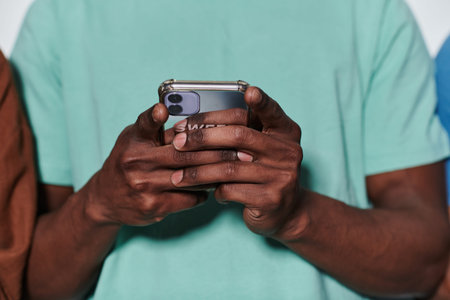 African American teenager engages with his smartphone against a pristine white background,...