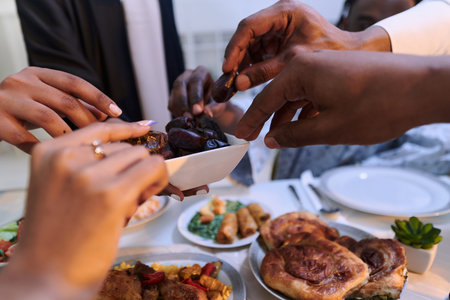 In a poignant close-up, the diverse hands of a Muslim family delicately grasp fresh dates,...